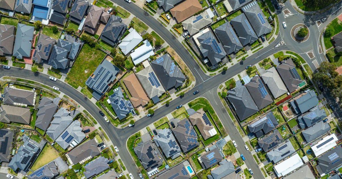 Aerial view of a suburban neighborhood with curving streets, a roundabout and rows of houses.